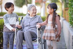 車いすの女性と子どもたちが外で過ごす様子